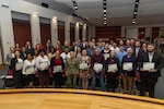 Mentors and mentees pose for a photo with DLA Weapons Support (Columbus) Commander Navy Rear Adm. Julie Treanor after the 2025-2026 Mentoring Program graduation ceremony April 17.  The ceremony, held in the agency's Operations Center Auditorium, celebrated  the dedication and resilience of 33 mentees and 33 mentors. (Photo by Andrew Young/DSCC)