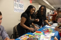 A Portfolio Acquisition Executive (PAE) Strategic Systems Programs (SSP) employee supports children in building their own small, home-made aircraft at command headquarters in Washington D.C., on April 23, 2026. PAE SSP welcomed more than 275 children to the command’s headquarters in Washington D.C., to learn about their parents’ day-to-day job supporting the U.S. Navy’s strategic deterrence mission.