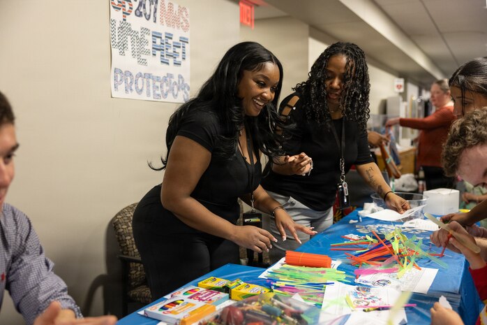 A Portfolio Acquisition Executive (PAE) Strategic Systems Programs (SSP) employee supports children in building their own small, home-made aircraft at command headquarters in Washington D.C., on April 23, 2026. PAE SSP welcomed more than 275 children to the command’s headquarters in Washington D.C., to learn about their parents’ day-to-day job supporting the U.S. Navy’s strategic deterrence mission.