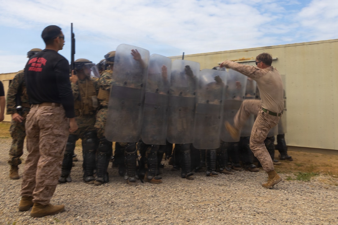 U.S. Marines with 2nd Battalion, 5th Marine Regiment, 1st Marine Division, hold the line against a simulated protestor as part of riot control training during a non-lethal weapons course at Marine Corps Base Camp Pendleton, California, April 30, 2026.