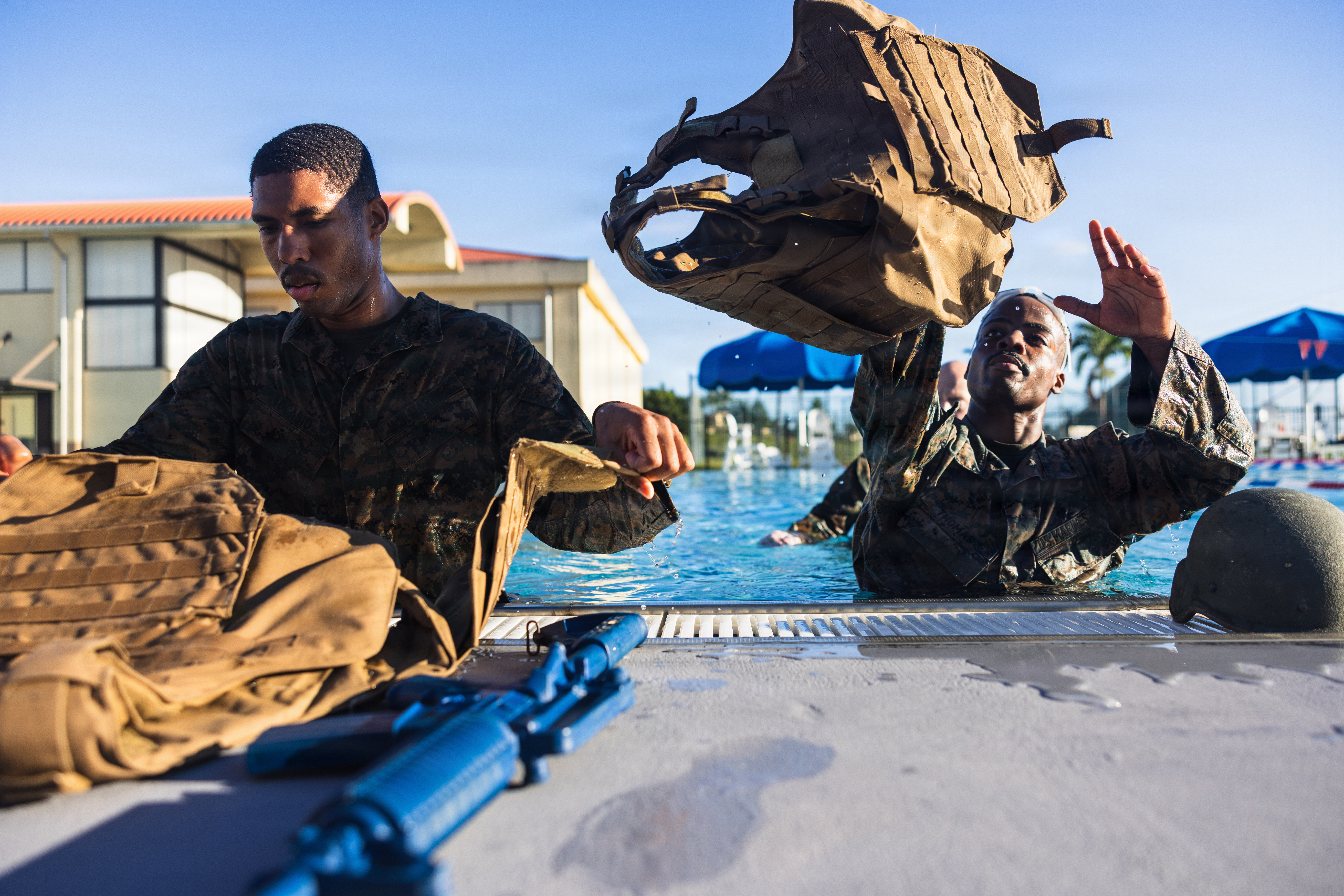U.S. Marine Corps Staff Sgt. Mark Ocasio, data systems chief, and Sgt. Rodencia Thomas, administrative specialist, Headquarters Company, Marine Corps Base Camp Blaz, prepare for a gear shed during a basic swim qualification on Naval Base Guam, March 26, 2026. The basic swim qualification consists of a 25-meter swim, tower jump into the water, four-minute tread, 25-meter pack swim, and an underwater gear shed. (U.S. Marine Corps photo by Sgt. Brayden Daniel)