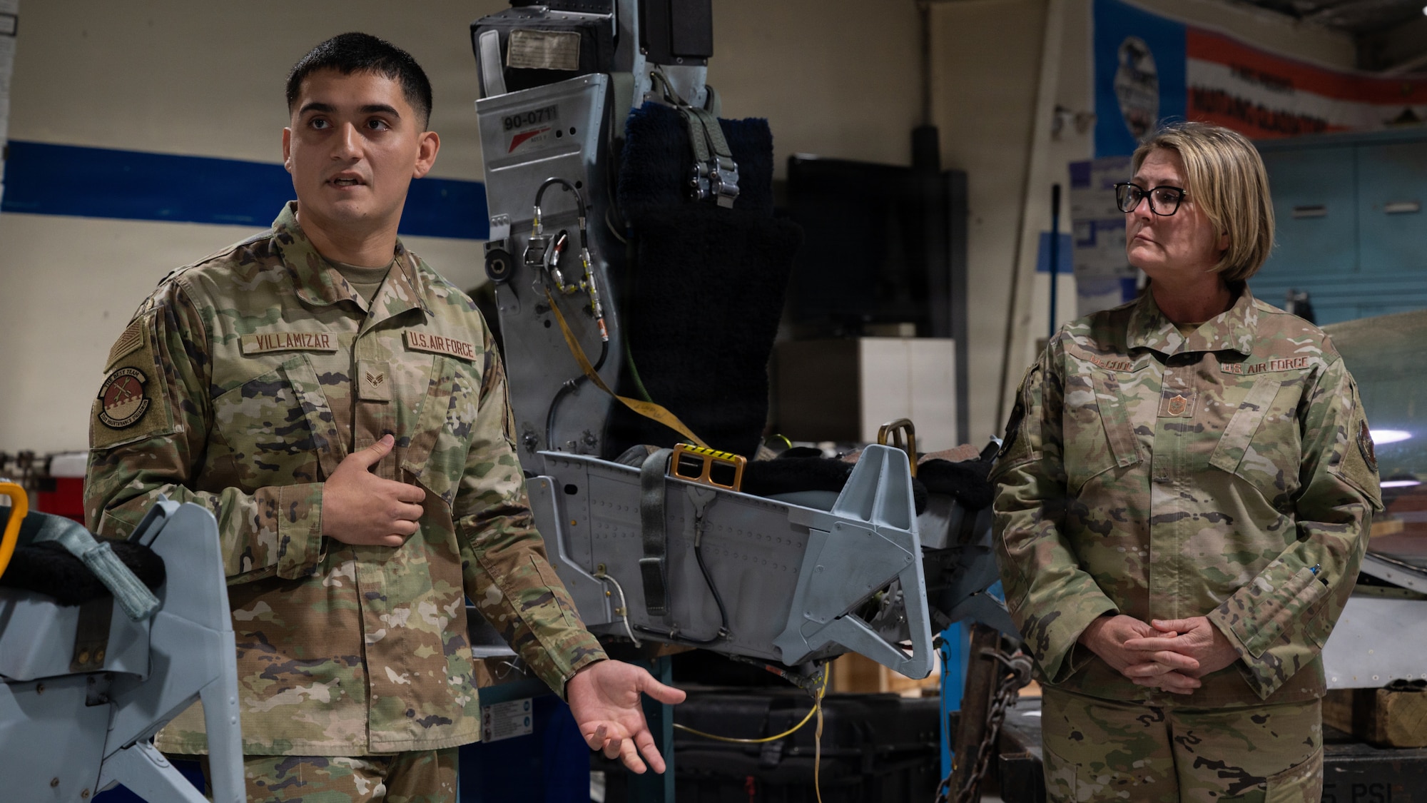 U.S. Air Force Senior Airman Giovanni Villamizar, 51st Maintenance Squadron egress systems journeyman, delivers a briefing on aircraft escape systems to Chief Master Sgt. Katie McCool, Pacific Air Forces command chief, at Osan Air Base, Republic of Korea, April 23, 2026. Egress systems technicians are responsible for inspecting, maintaining, and repairing escape systems — such as ejection seats and canopy initiators — for F-16 Fighting Falcons. (U.S. Air Force photo by Senior Airman Jessica Mun)