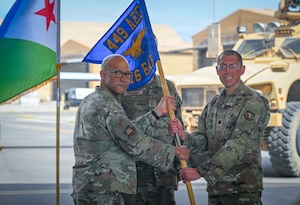 U.S. Air Force Col. Kris Aikens, 449th Air Expeditionary Group Commander, left, passes the guidon to U.S. Air Force Lt. Col Geoffrey Cohan, right, as he takes command of the 776th Expeditionary Air Base Squadron during a change of command ceremony at Chabelley Airfield, Djibouti, April 24, 2026. The ceremony celebrated the successful tenure of the outgoing commander and welcomed the inbound commander. (U.S. Army photo by SGT Vivian Nakaana)
