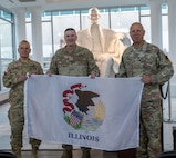 Brig. Gen. Lenny Williams, Assistant Adjutant General – Army and Commander of the Illinois Army National Guard, and Chief Warrant Officer 5 Thomas Black, Command Chief Warrant Officer, Illinois National Guard, present Chief Warrant Officer 5 Michael Maroon, Commander of Detachment 5, Company A, 2nd Battalion, 245th Aviation Regiment, with the state of Illinois flag which will accompany the unit on its upcoming mission to the U.S. Southern Command area of responsibility.