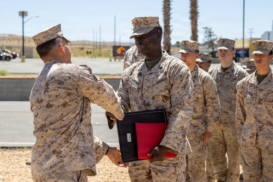 #marines stand in formation for Sergeant Joseph Kwitonda in front of the Eagle, Globe, and Anchor statue aboard Marine Corps Logistics Base Barstow. California, May 1. Sgt. Kwitonda was awarded an Achievement medal by Colonel Russell Savatt, base commanding officer, on his final day of service after seven years, mainly with the Marine Corps Mounted Color Guard; delivering remarks reflecting on his military experience and thanking those who supported him.