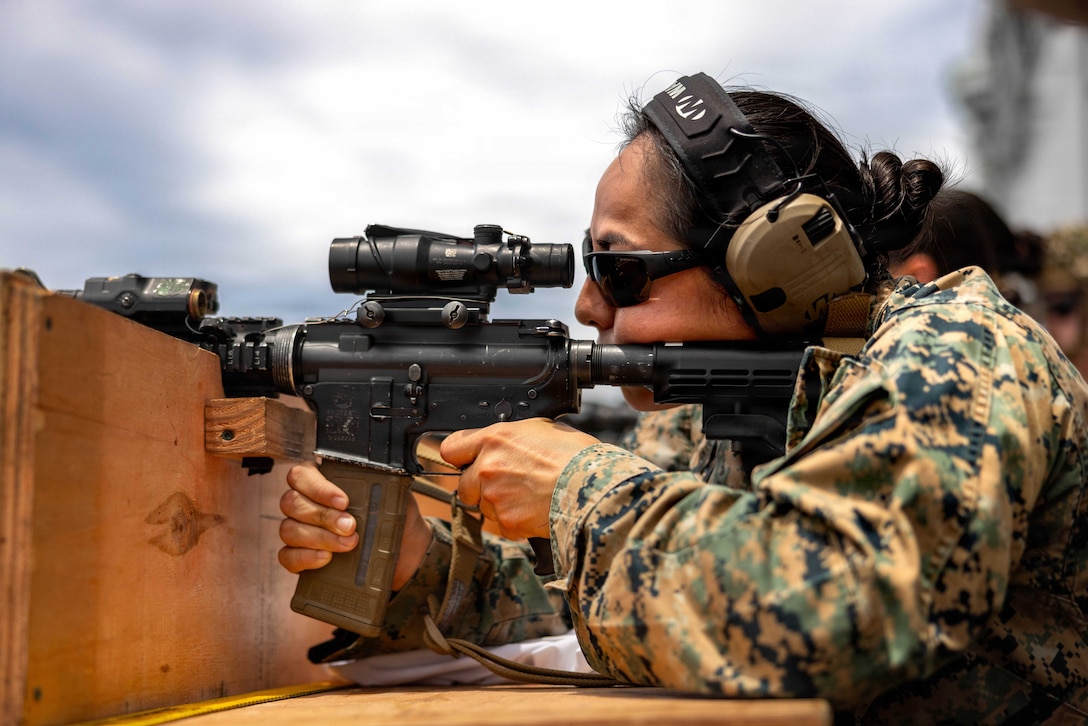 A soldier wearing sunglasses holds a firearm in a shooting position during training.