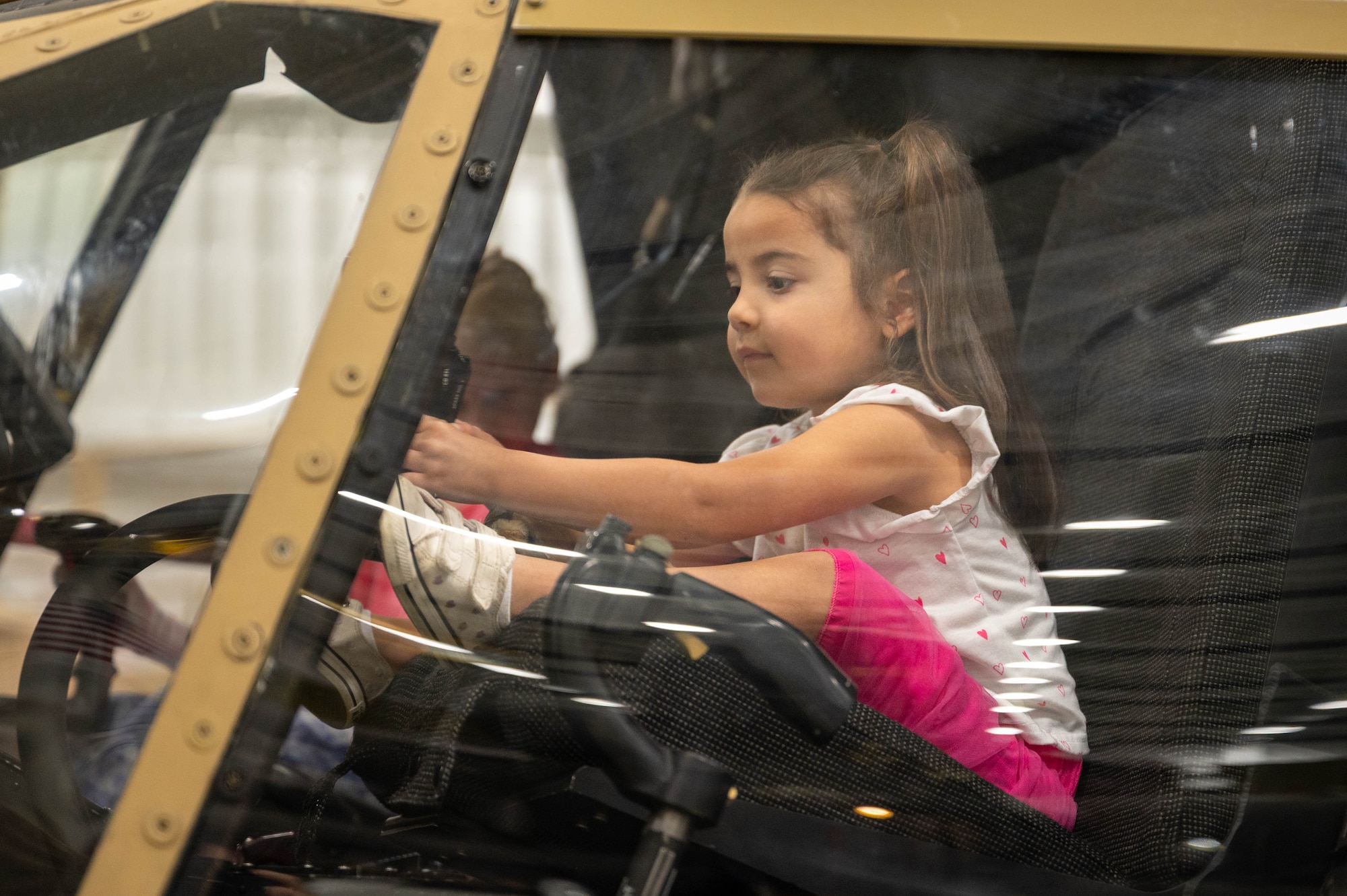 Photo shows a child inside of an aircraft cockpit holding on to the cyclic control.