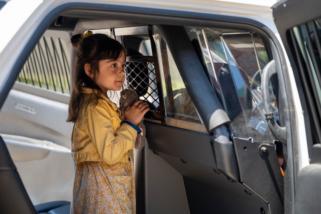 Photo shows a child standing in the back of a military police vehicle.