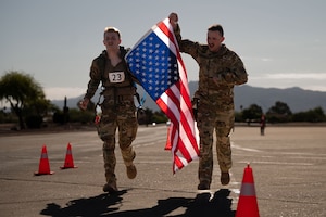 U.S. Air Force Airman 1st Class Riley Friede, left, and U.S. Air Force Staff Sgt. Nicholas McGinnis, right, both assigned to the 42nd Electronic Combat Squadron, cross the finish line of the Norwegian Foot March held at Davis-Monthan Air Force Base, Arizona, May 2, 2026. Friede crossed the finish line with minutes left in order to receive his Norwegian Foot March badge. (U.S. Air Force photo by Airman Najzee Kuzu)