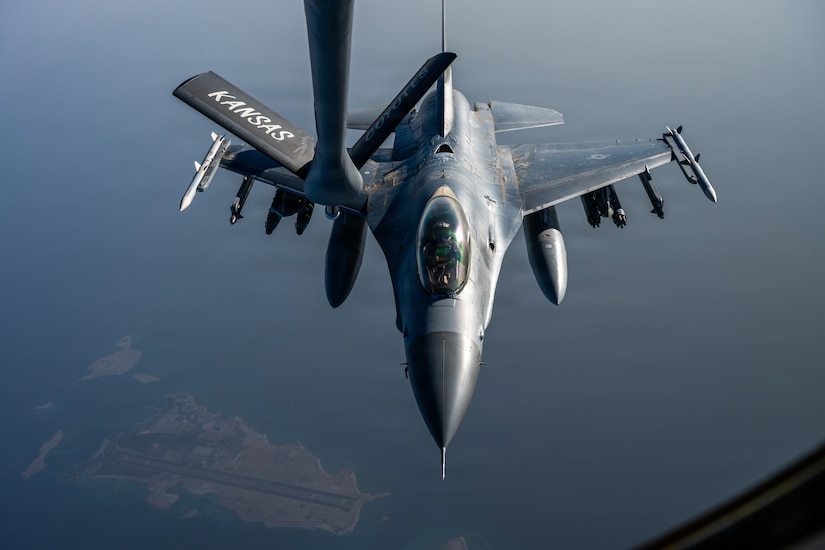 An aircraft flies over open water.