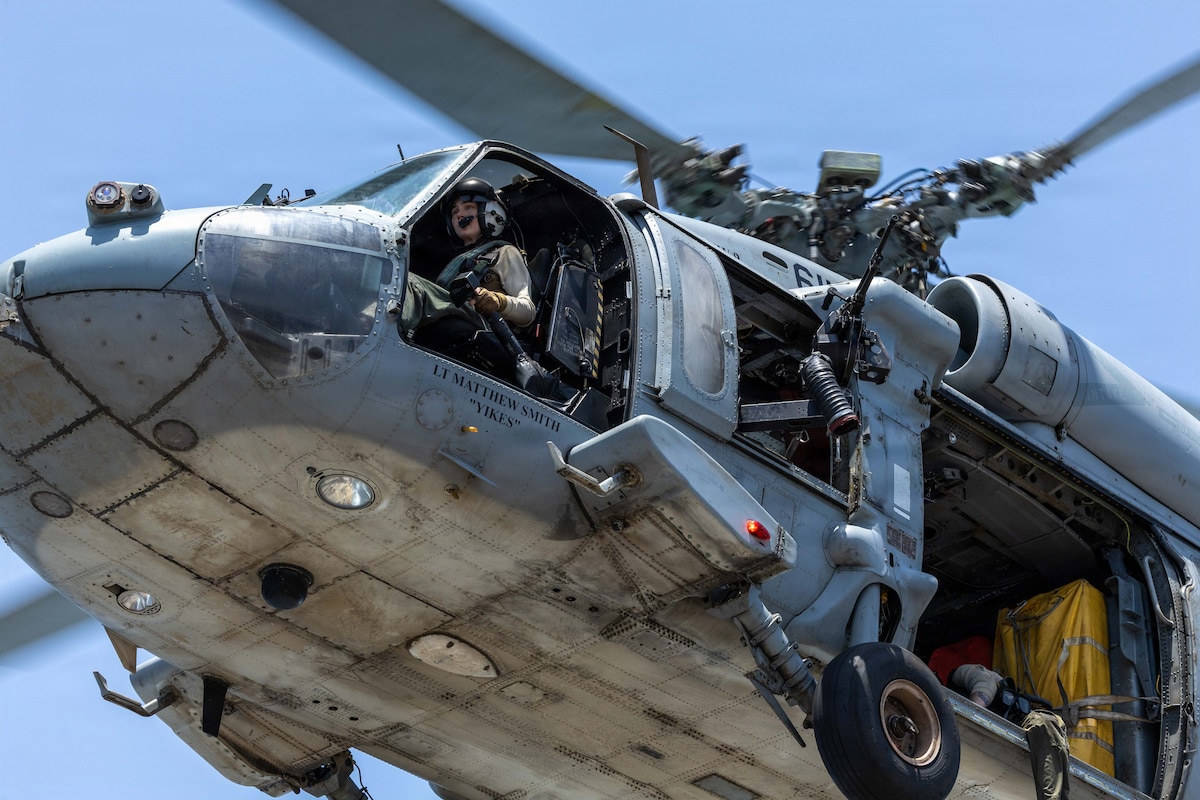 A helicopter lifts off in this close up image. The pilot is seated in the cockpit.