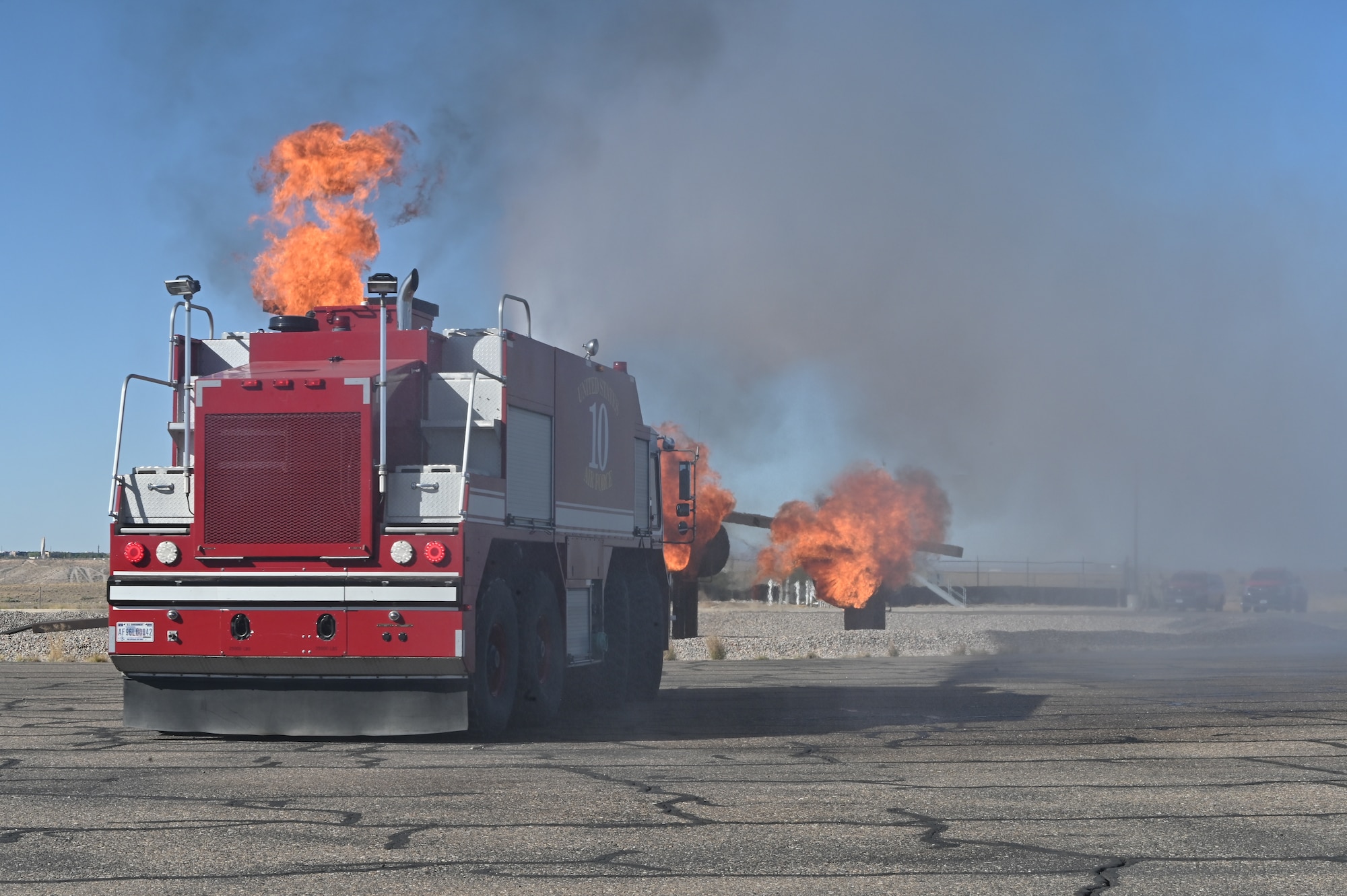 A fire truck from the 377th Civil Engineer Squadron fire protection team extinguishes a simulated aircraft burn pit as part of a Kirtland Air Force Base Fire and Emergency Services (KFES) exercise.