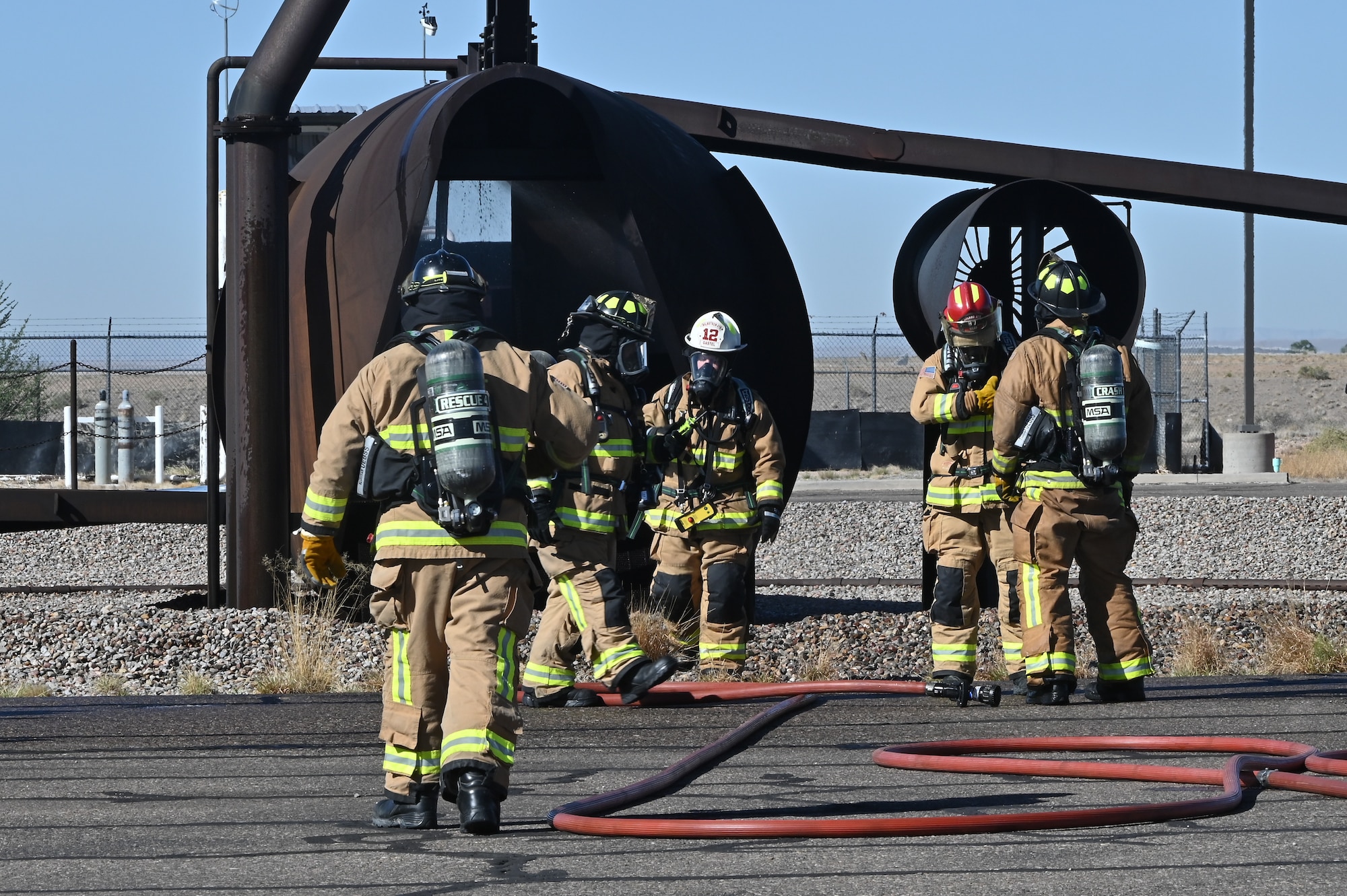 Team Kirtland fire protection specialists extinguish a simulated aircraft burn pit as part of a Kirtland Air Force Base Fire and Emergency Services (KFES) exercise.