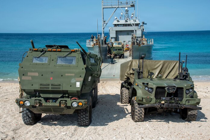 A U.S. Marine Corps Navy-Marine Expeditionary Ship Interdiction System, right, assigned 3rd Littoral Combat Team, 3rd Marine Littoral Regiment, 3rd Marine Division, and a U.S. Army M142 High Mobility Artillery Rocket System assigned to 7th Infantry Division, Multi-Domain Command - Pacific, are staged on the beach after a joint ship-to-shore movement during Exercise Balikatan 2026 in Calayan, Cagayan, Philippines, April 28, 2026.