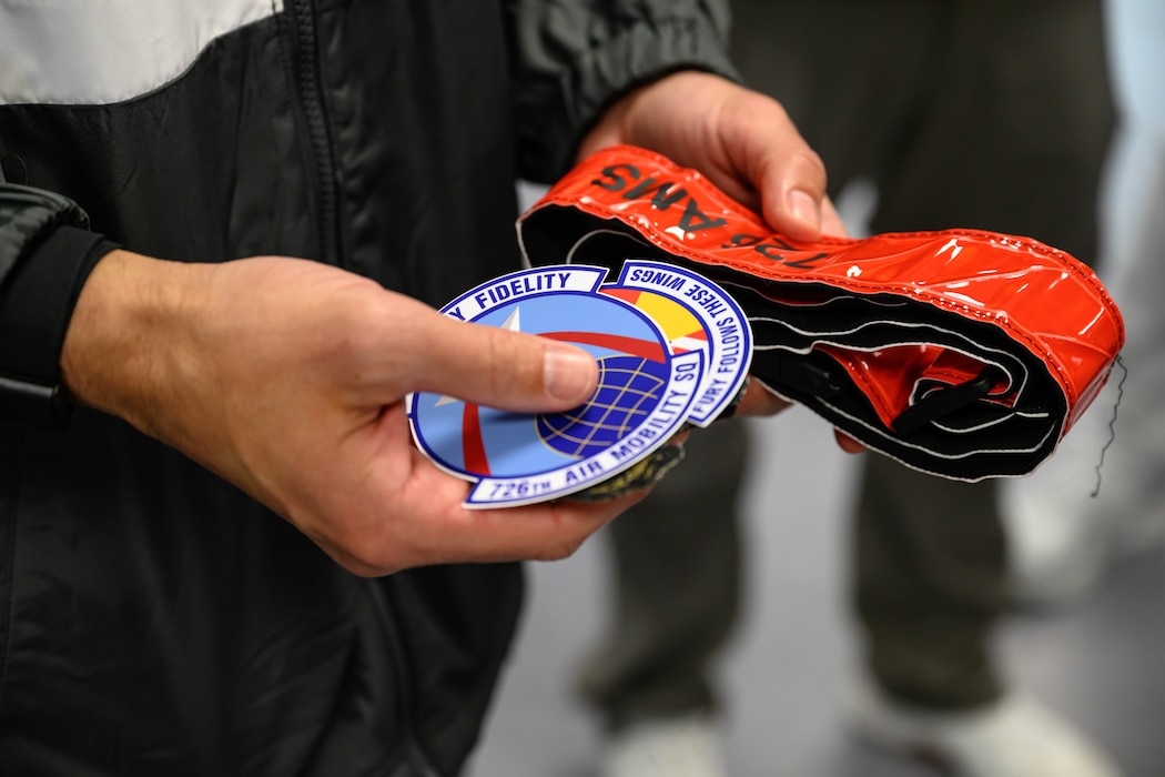 A person holds U.S. Air Force 726th Air Mobility Squadron memorabilia.