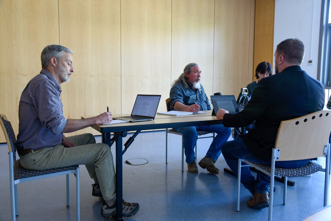 people sitting around a table talking and taking notes