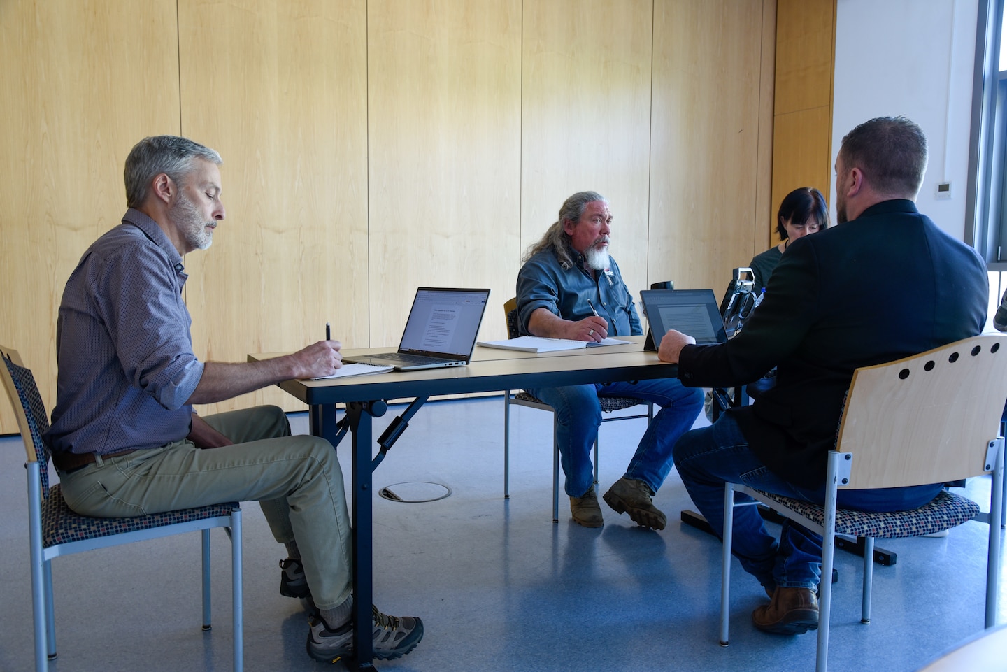 people sitting around a table talking and taking notes