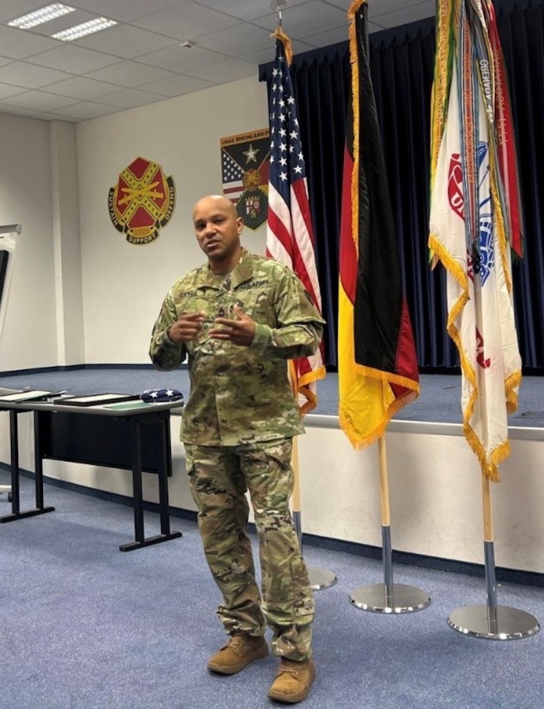 man standing in front of three flags that are propped against a wall
