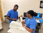 Lt. j.g. Karl Cormier, left, an occupational therapist assigned to U.S. Naval Hospital (USNH) Guam, trains Hospital Corpsman 2nd Class Alexis Hawkins on splinting techniques. In addition to training the U.S. Navy physical therapists and physical therapy technicians at the hospital, Cormier led training for U.S. Air Force physical therapy technicians from the 36th Medical Group, Andersen Air Force Base, focused on splinting as well as essential inpatient rehabilitation skills. The training equipped therapists and technicians with the knowledge and hands-on experience needed to support patient care in both clinical and operational settings. Cormier has played a key role in expanding patient access to care and advancing joint medical readiness while elevating the quality of trauma and inpatient rehabilitation services. Through targeted process improvements and a focus on high-acuity care, Cormier has helped ensure timely, effective treatment for service members and beneficiaries across the island.