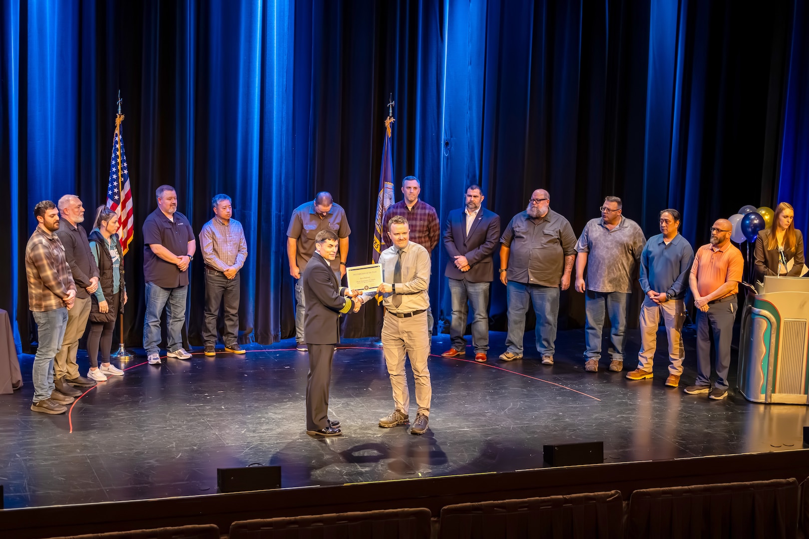 Capt. JD Crinklaw, commander, Puget Sound Naval Shipyard & Intermediate Maintenance Facility, presents Dane Bargerstock, Code 297, with an award in the Engineering or Technical (non-degreed) category, April 22, 2026, during the annual Employee of the Year ceremony at the Admiral Theatre in downtown Bremerton, Washington. (U.S. Navy photo by Jeb Fach)