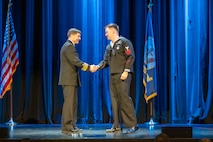Capt. JD Crinklaw, commander, Puget Sound Naval Shipyard & Intermediate Maintenance Facility, congratulates the 2025 Sailor of the Year, Yeoman Submarine 1st Class Grant Plummer during the annual Employee of the Year ceremony at the Admiral Theatre in downtown Bremerton, Washington.. (U.S. Navy photo by Wendy Hallmark)
