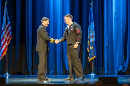 Capt. JD Crinklaw, commander, Puget Sound Naval Shipyard & Intermediate Maintenance Facility, congratulates the 2025 Sailor of the Year, Yeoman Submarine 1st Class Grant Plummer during the annual Employee of the Year ceremony at the Admiral Theatre in downtown Bremerton, Washington.. (U.S. Navy photo by Wendy Hallmark)