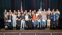 Capt. JD Crinklaw, commander, Puget Sound Naval Shipyard & Intermediate Maintenance Facility, poses for a group picture with the 2025 Employees of the Year during the annual Employee of the Year ceremony at the Admiral Theatre in downtown Bremerton, Washington. (U.S. Navy photo by Wendy Hallmark)