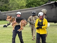 Rescue Team members unload Jack, a German Shepherd, from a Tennessee Army National Guard Black Hawk helicopter after a rescue.