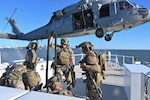 Coast Guard deployable specialized forces assigned to the Coast Guard Maritime Security Team – East stow a fast rope during training with a U.S. Navy MH-60S Seahawk helicopter aircrew from the Helicopter Sea Combat – Squadron 11 (HSC-11) while underway aboard Coast Guard Cutter Richard Snyder (WPC 1127) on the James River in Newport News, Virginia, Oct. 22, 2025. Coast Guard DSF personnel conducted boarding team delivery and fast-rope training with HSC-11 to increase interoperability and enable team member qualification. (U.S. Coast Guard photo by Petty Officer 2nd Class Brandon Hillard)