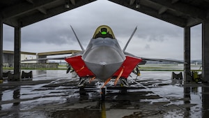A military jet is parked under a hangar.