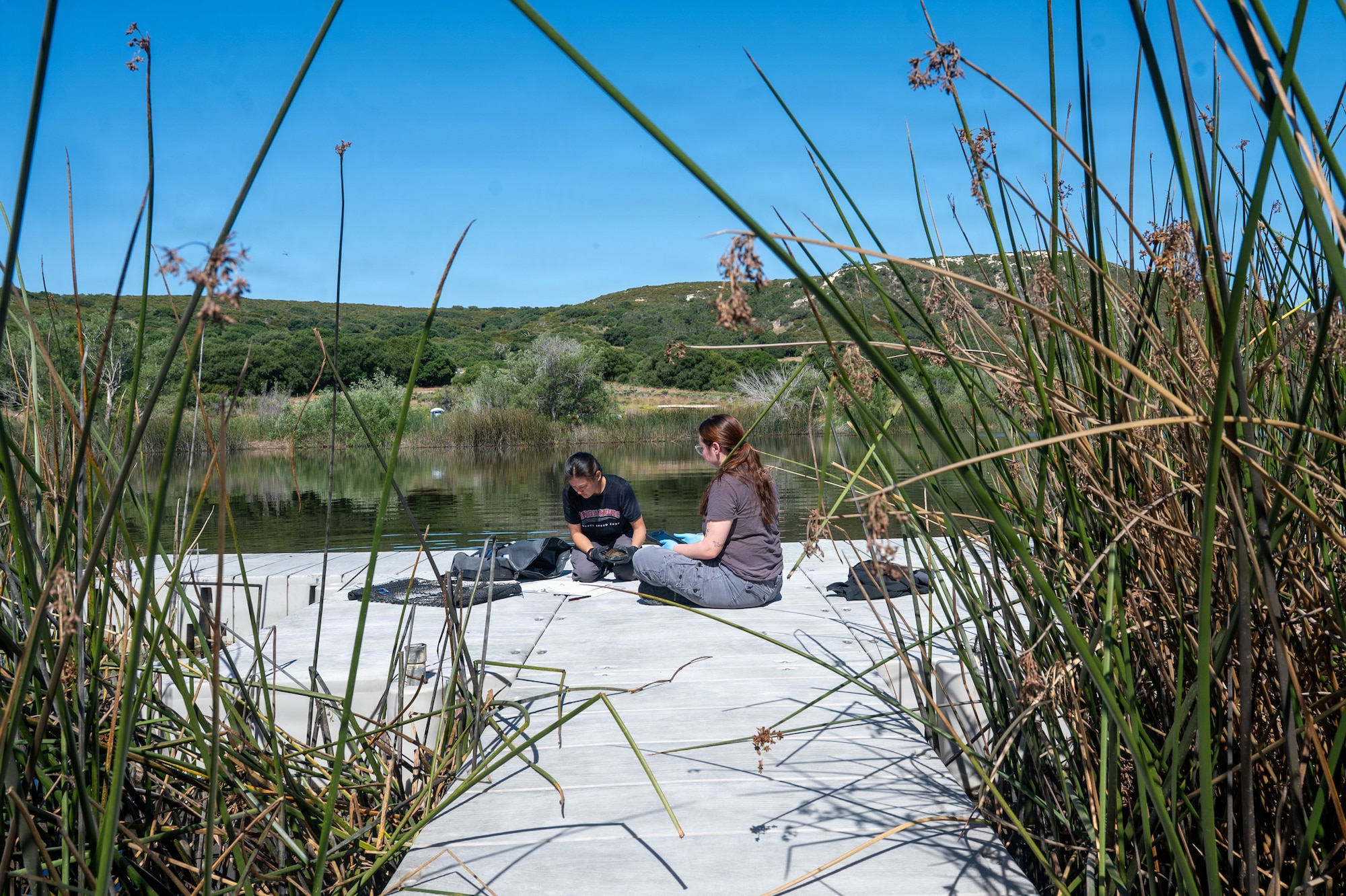 Two people sit on a dock and discuss.