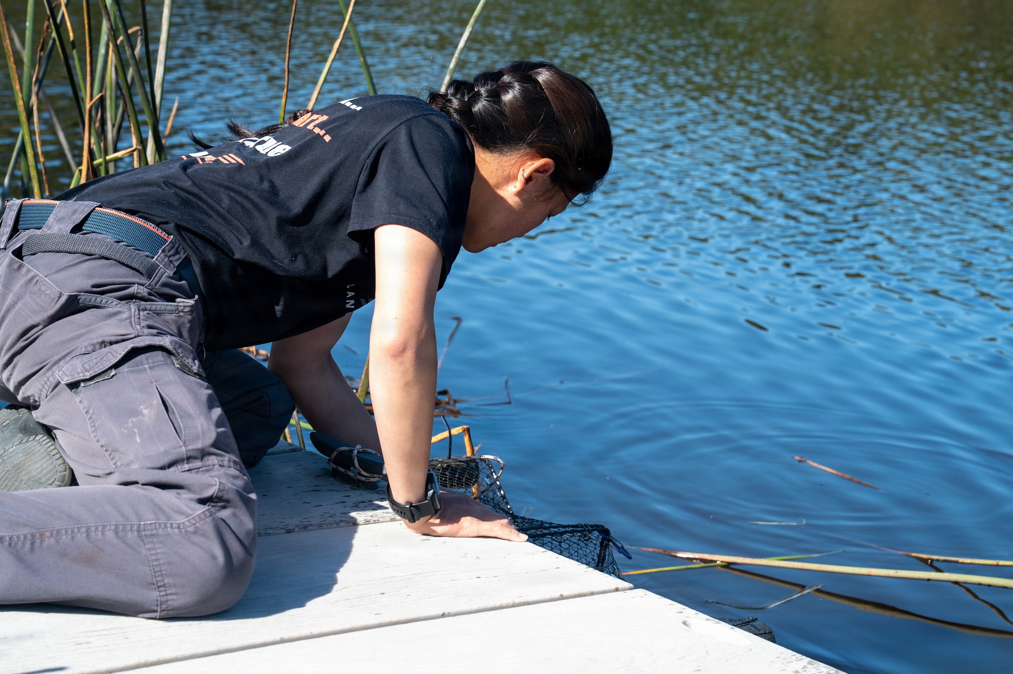 A person looks at the water and reaches for a trap.