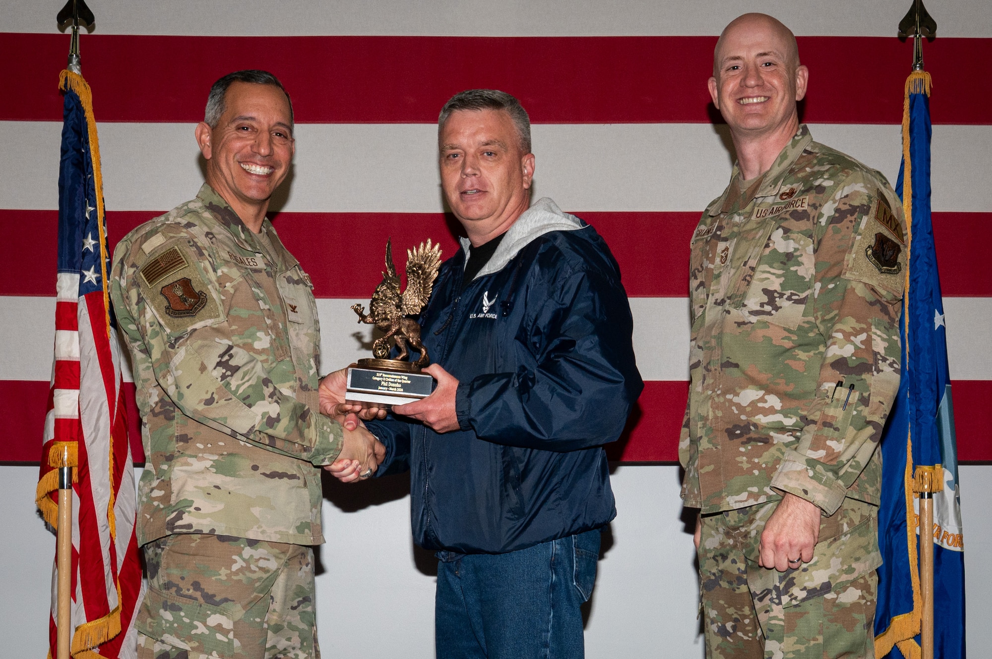 A photo of a group of people stands on a stage holding an award.