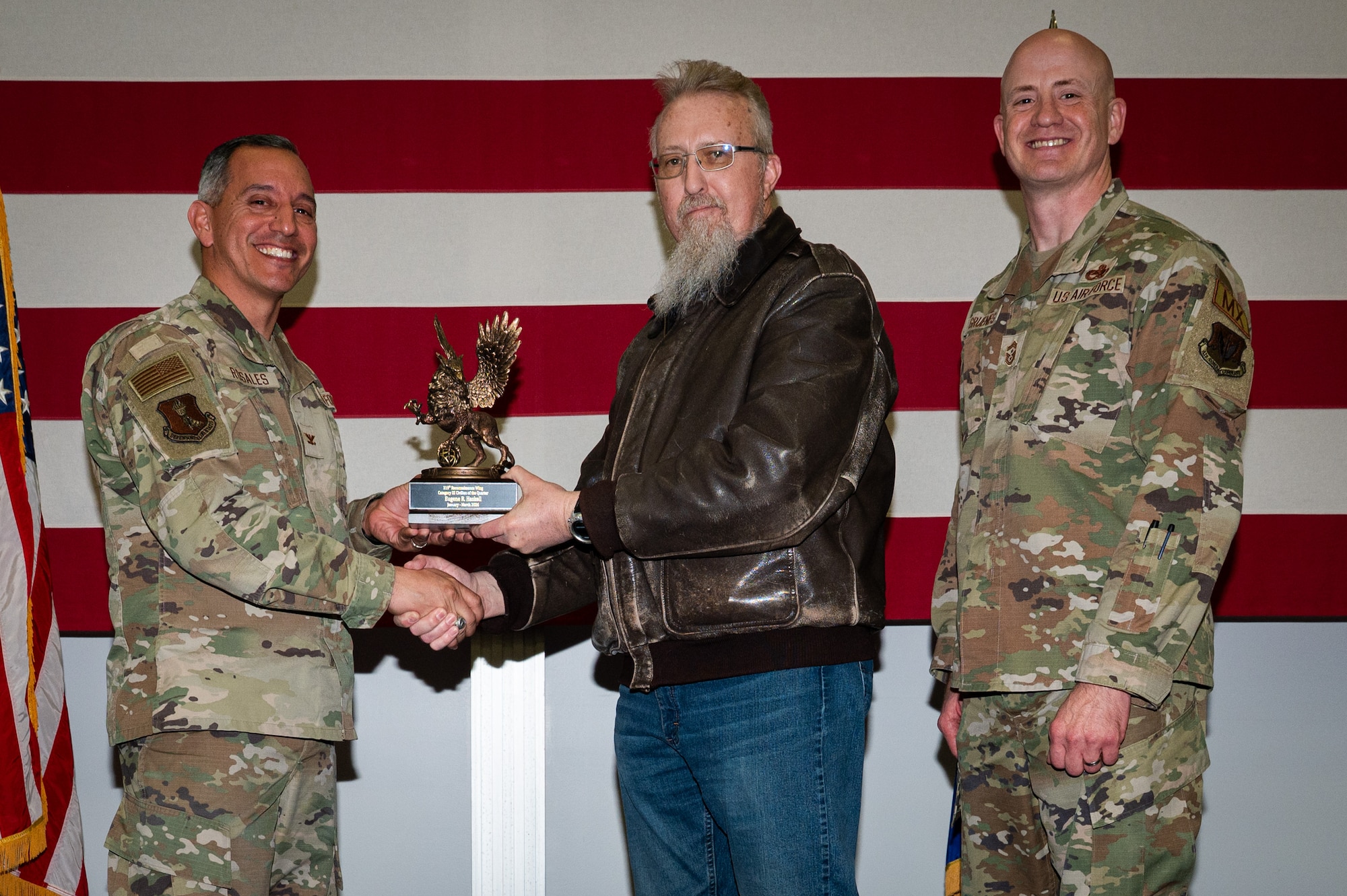 A photo of a group of people stands on a stage holding an award.
