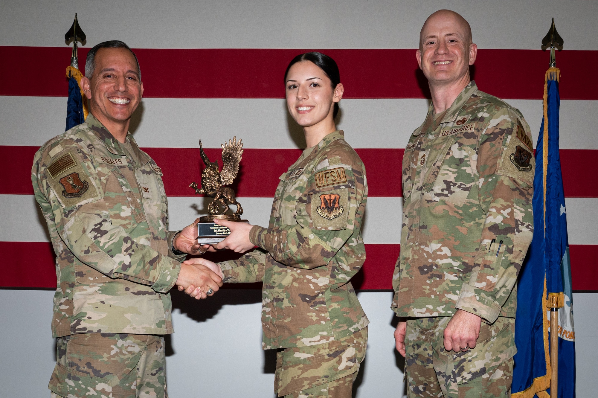 A photo of a group of people stands on a stage holding an award.