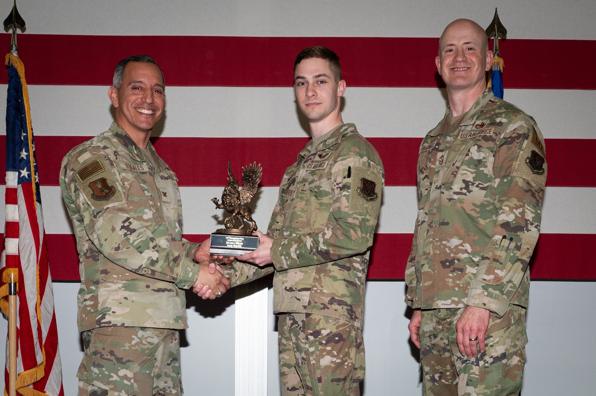 A photo of a group of people stands on a stage holding an award.