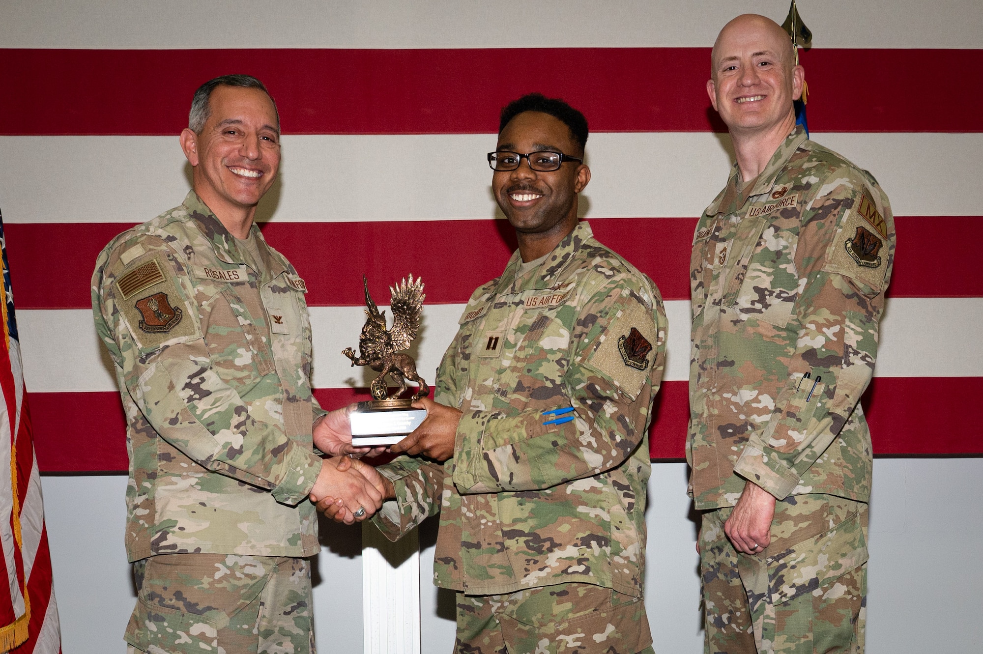 A photo of a group of people stands on a stage holding an award.
