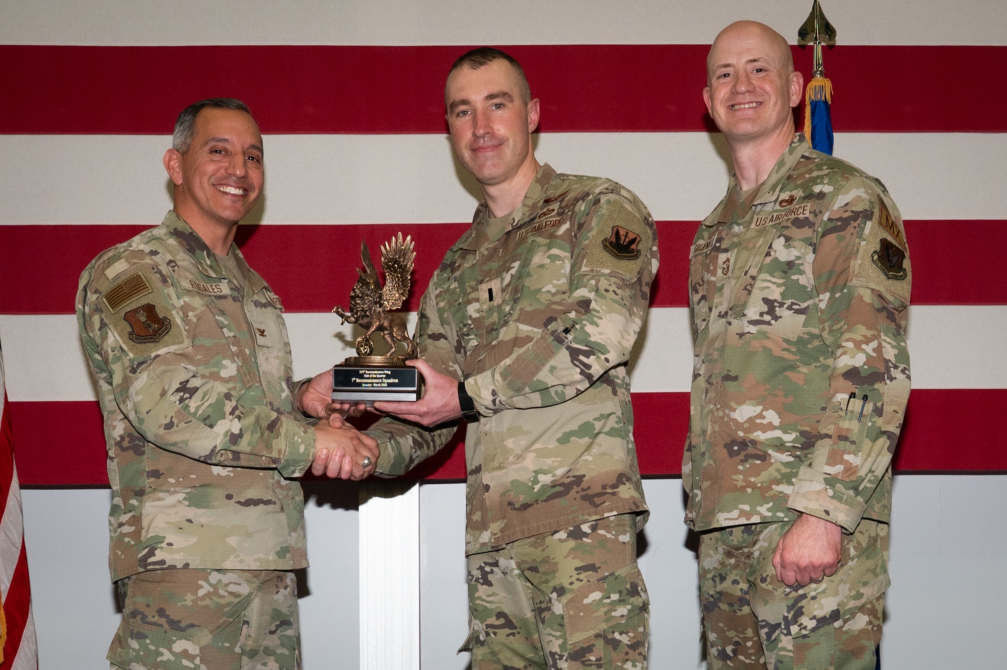 A photo of a group of people stands on a stage holding an award.
