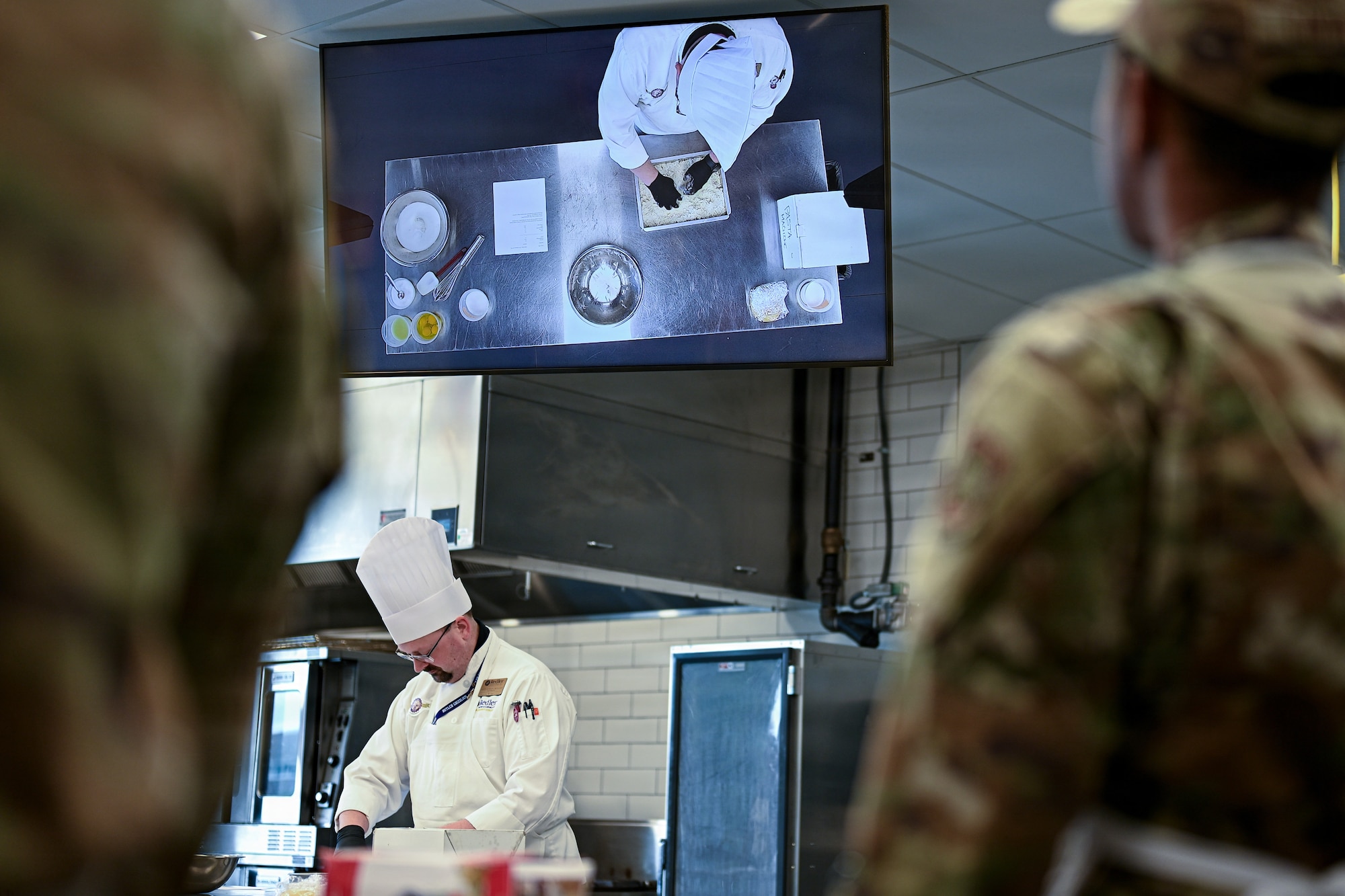 Chef Ethan Moulds, Redler Institute of Culinary Arts head instructor, demonstrates various cooking techniques to dining facility Airmen of the 22nd Force Support Squadron in Andover, Kansas, April 28, 2026. The DFAC Airmen participated in a partnered program between Redler and McConnell Air Force Base designed to teach them new culinary skills.  (U.S. Air Force photo by Senior Airman Amelio Brown)
