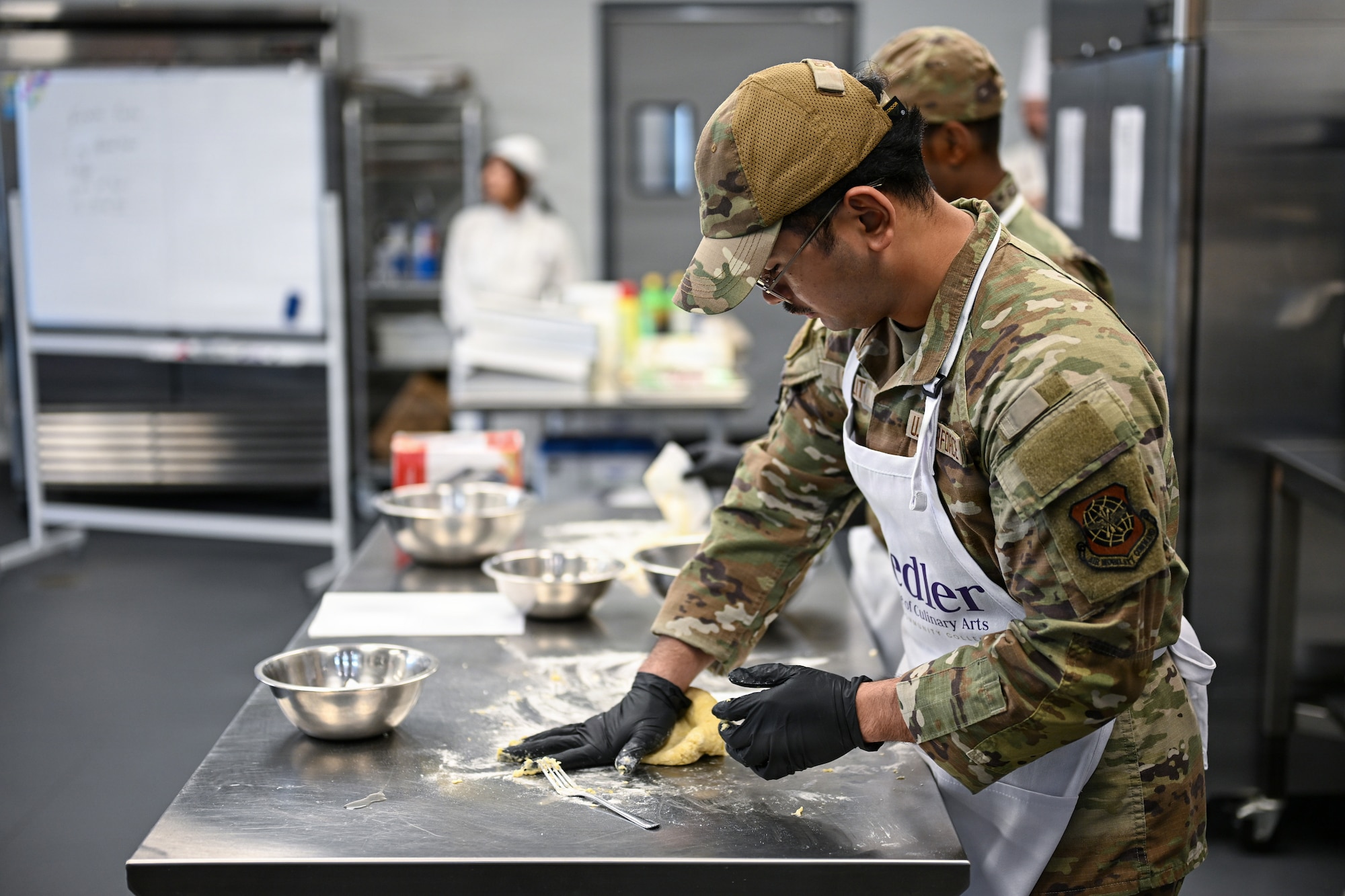 Airman First Class Gian Sulit, 22nd Force Support Squadron Airman, kneads a ball of dough at the Redler Institute of Culinary Arts in Andover, Kansas, April 28, 2026. McConnell Air Force Base’s DFAC Airmen visited the institute for a day of instruction and hands-on experience with culinary experts. (U.S. Air Force photo by Senior Airman Amelio Brown)