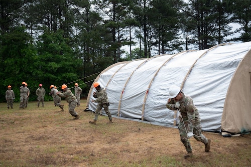 Airmen use ropes to pull up a tent