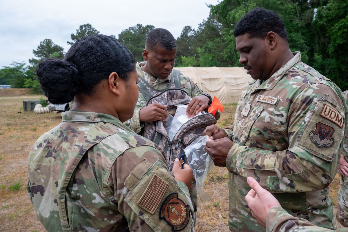 Airmen put a plastic bag in a backpack