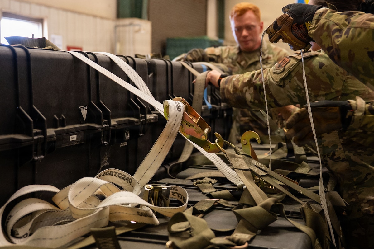 Airmen tighten straps on a pallet