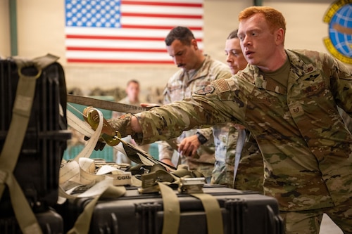 An Airman tightens a strap on a pallet