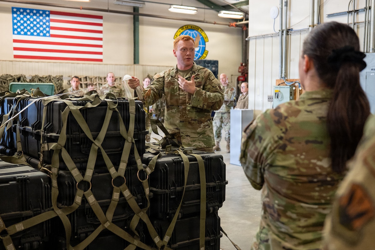 An Airman gives a briefing to other Airmen by a pallet