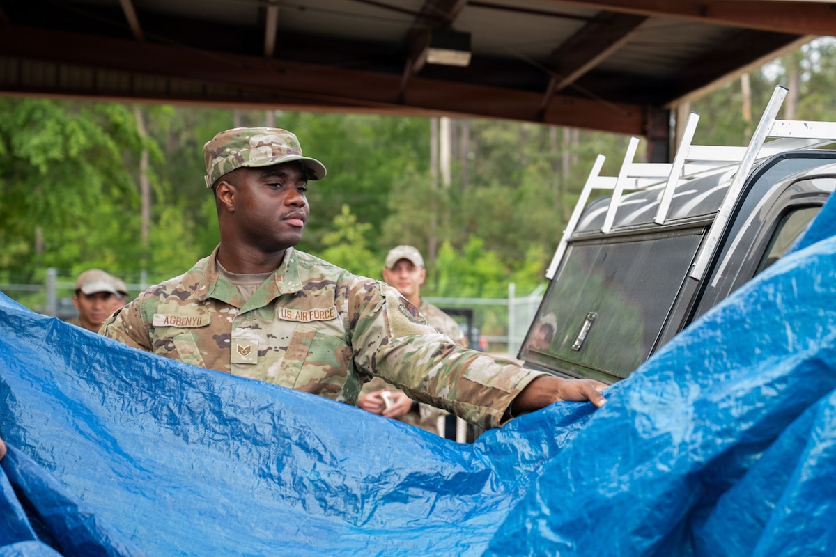 An Airman unfurls a tarp