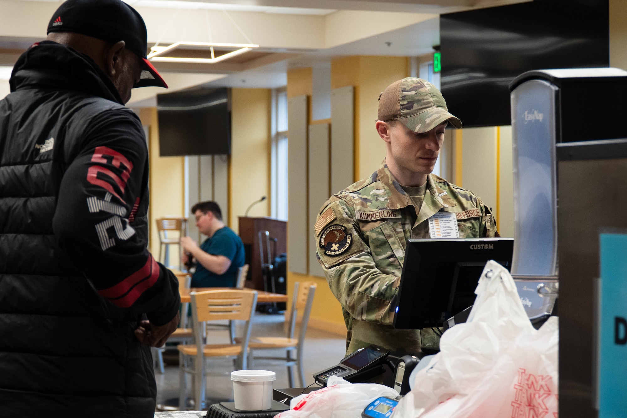 U.S. Air Force Senior Airman Jacob Kummerling, 673d Medical Support Squadron diet technician, assists a customer at the hospital dining facility on Joint Base Elmendorf-Richardson, Alaska, May 4, 2026. Members of the Nutritional Medicine Flight oversee culinary operations to ensure service members and medical personnel have access to performance-based nutrition that supports the installation's mission readiness. (U.S. Air Force photo by Airman 1st Class Keola Vischi)
