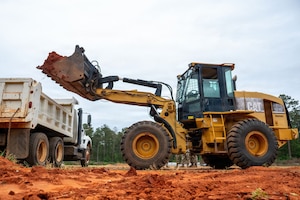 A front-end loader dumps dirt into a trcuk