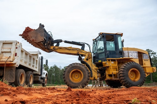 A front-end loader dumps dirt into a trcuk