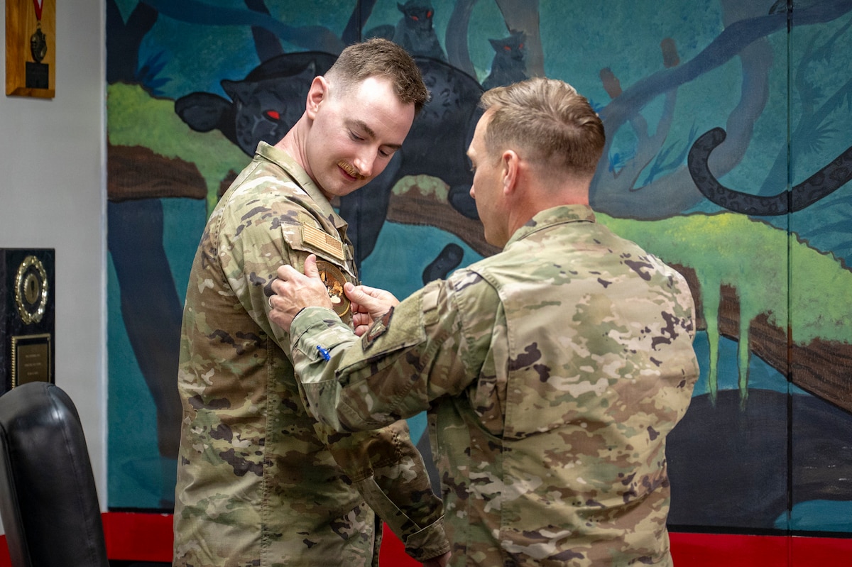 U.S. Air Force Col. Paul Davidson, 35th Fighter Wing commander, places a patch on Staff Sgt. Stephen Terrick, 13th Fighter Generation Squadron noncommissioned officer in charge of maintenance managers, during a Wild Weasel Walk-through at Misawa Air Base, Japan, May 4, 2026. Davidson recognized Terrick as Wild Weasel of the Week for his performance in managing aircraft maintenance timelines and coordinating repair efforts, ensuring continuous airpower projection. (U.S. Air Force photo by Senior Airman Brittany Russell)